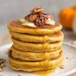 Side view of 5 stacked pumpkin pancakes on a white plate